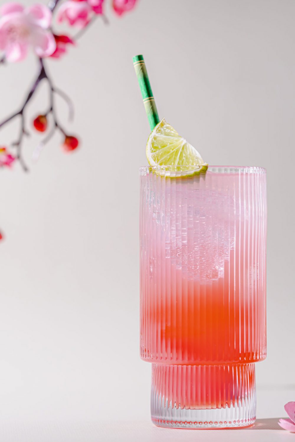 Summer refreshing drink. Light pink rose cocktail on a white background with spring flowers.